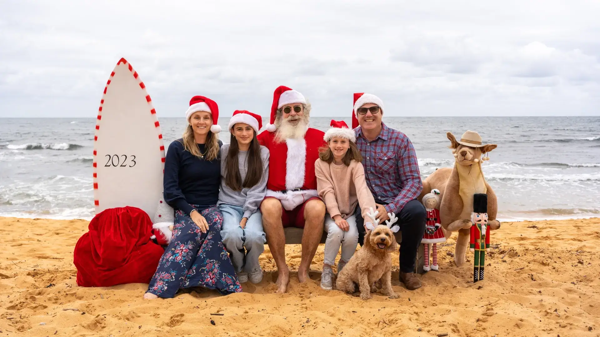 Happy family with their dog having a photo session with Santa at the Beach